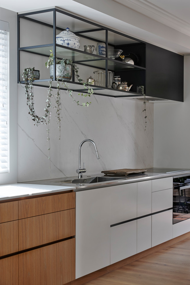 Inspiration for a mid-sized traditional galley separate kitchen in Auckland with an integrated sink, brown cabinets, marble benchtops, white splashback, stainless steel appliances, medium hardwood floors, with island, brown floor and white benchtop.