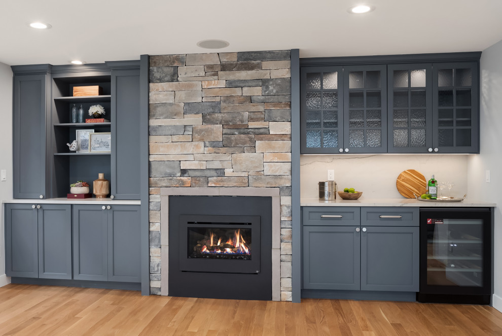 シアトルにあるトランジショナルスタイルのおしゃれなファミリールーム (ホームバー、青い壁、淡色無垢フローリング、標準型暖炉、石材の暖炉まわり、茶色い床) の写真