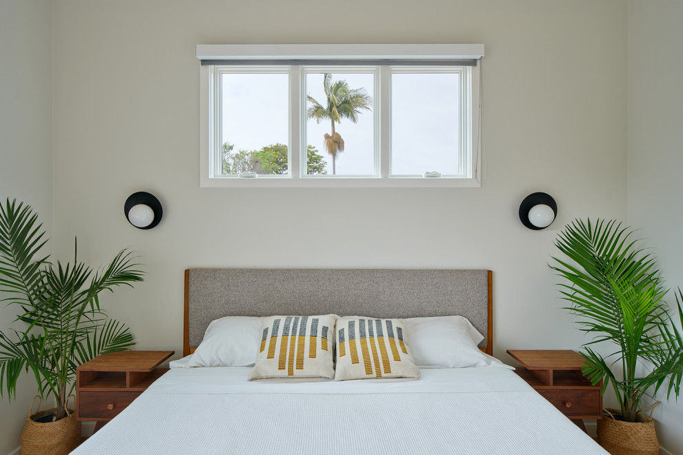 Cette image montre une chambre parentale minimaliste de taille moyenne avec un mur blanc, un sol en liège, un sol marron et un plafond voûté.