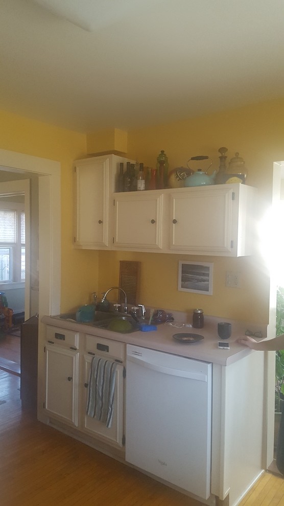 Inspiration for a transitional u-shaped light wood floor kitchen remodel with recessed-panel cabinets, white cabinets, laminate countertops, white appliances, no island, pink countertops and a drop-in sink
