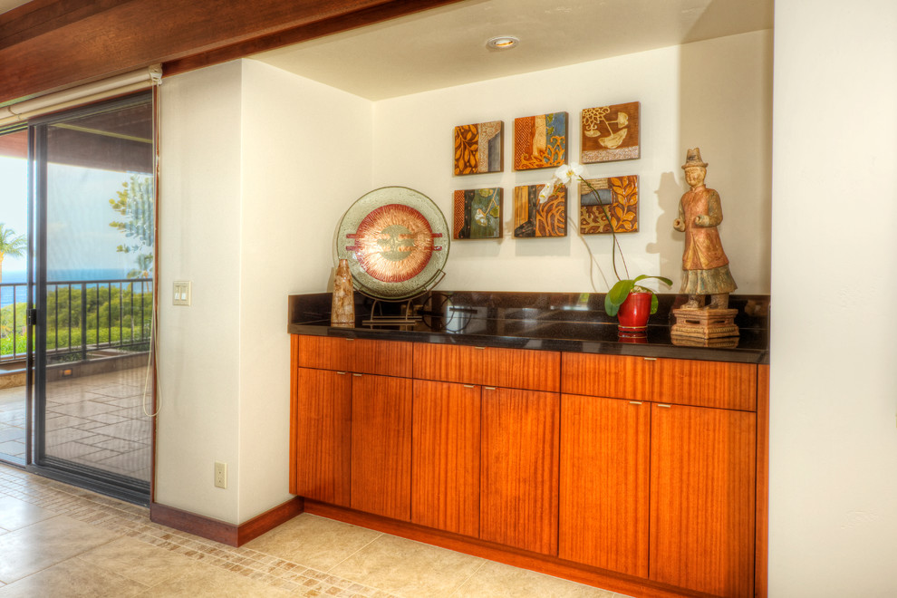 Photo of a mid-sized modern galley wet bar in Hawaii with flat-panel cabinets, medium wood cabinets, granite benchtops, black splashback, ceramic floors and beige floor.