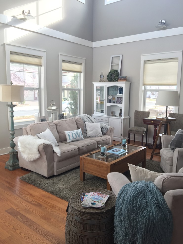 This is an example of a mid-sized beach style enclosed living room in Charlotte with grey walls, medium hardwood floors, no fireplace and brown floor.