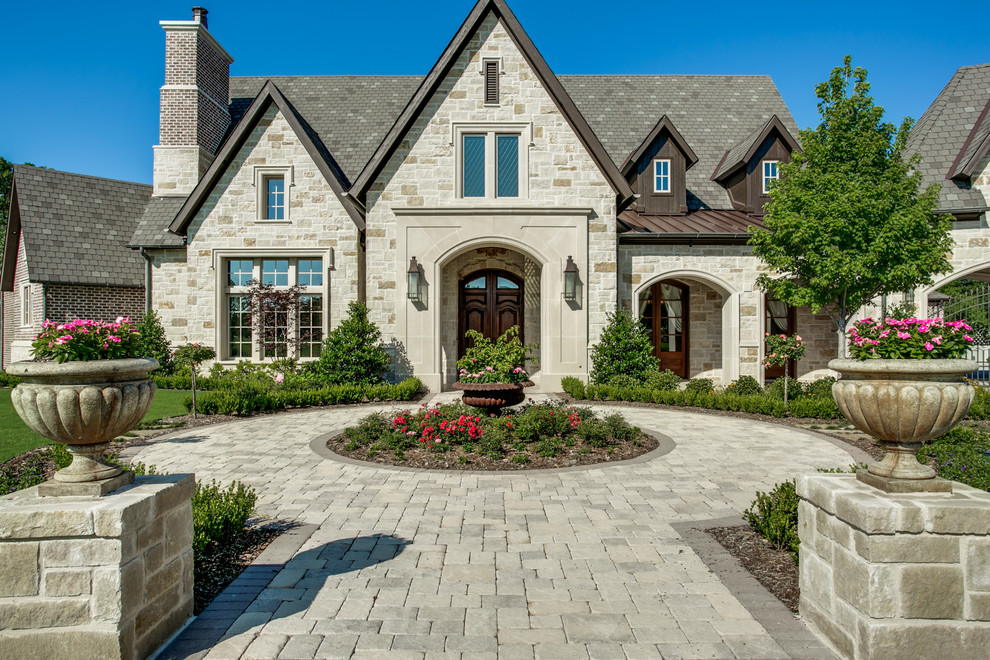 This is an example of a traditional two-storey beige exterior in Dallas with stone veneer and a gable roof.