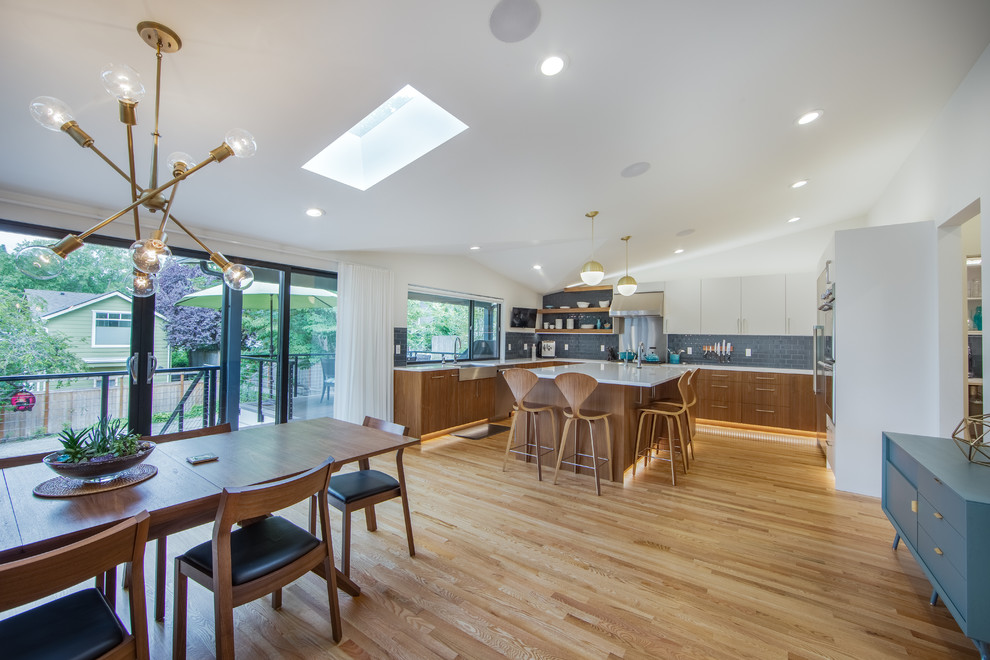 Inspiration for a midcentury u-shaped kitchen in Seattle with a farmhouse sink, flat-panel cabinets, dark wood cabinets, quartz benchtops, medium hardwood floors, with island, multi-coloured floor, white benchtop and vaulted.