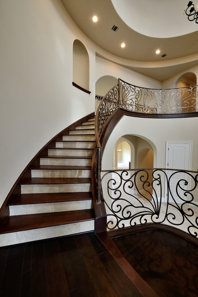 Design ideas for a large mediterranean wood curved staircase in Houston with travertine risers and metal railing.