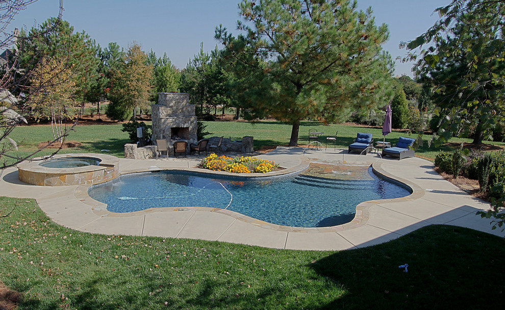 Example of a large mountain style backyard concrete paver and custom-shaped lap hot tub design in Charlotte