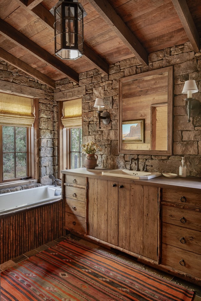 This is an example of a country master bathroom in Other with medium wood cabinets, a drop-in tub, a drop-in sink, grey benchtops and flat-panel cabinets.