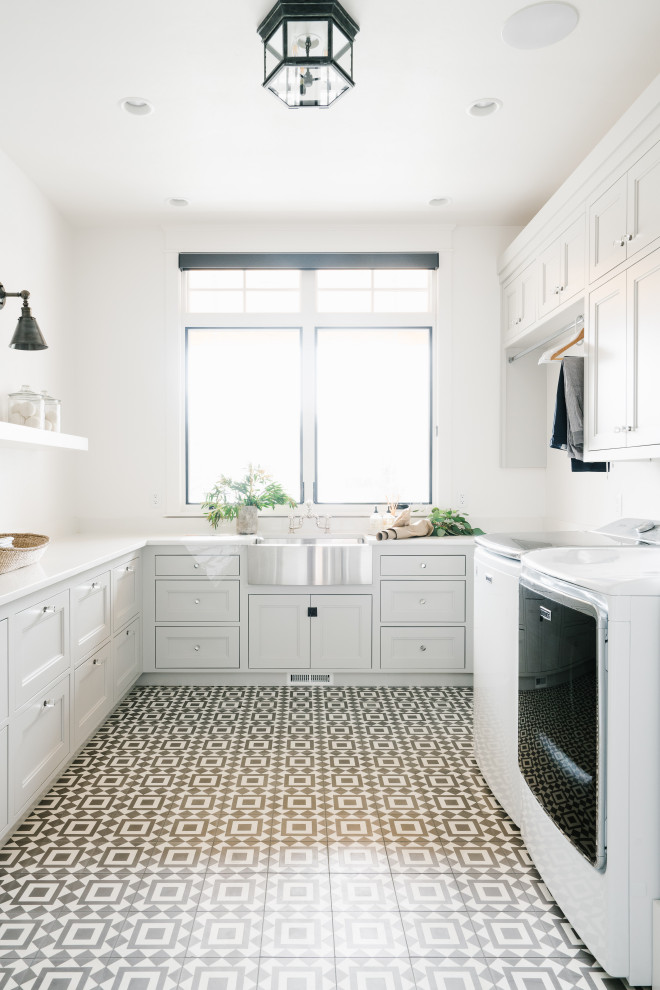 Transitional u-shaped dedicated laundry room in Salt Lake City with a farmhouse sink, beaded inset cabinets, white cabinets, white walls, a side-by-side washer and dryer, multi-coloured floor and white benchtop.