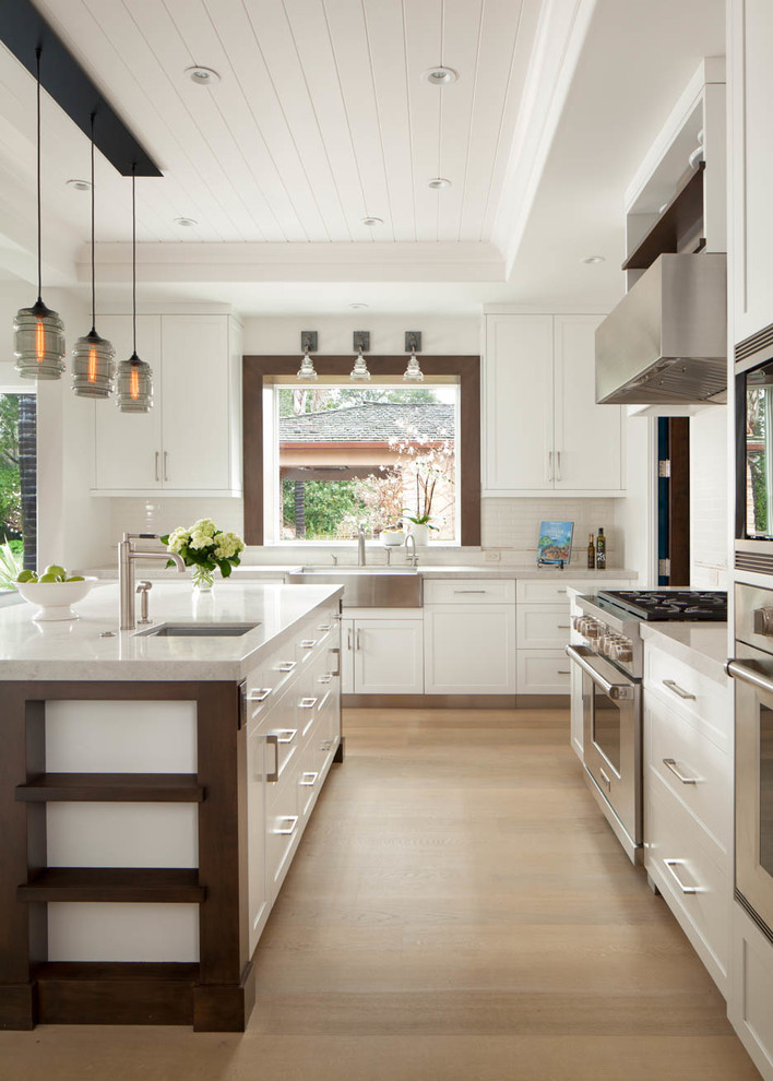 Country l-shaped open plan kitchen in San Francisco with a farmhouse sink, shaker cabinets, yellow cabinets, stainless steel appliances, light hardwood floors and with island.