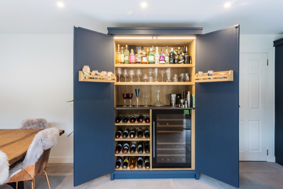 Inspiration for a large industrial l-shaped eat-in kitchen in Essex with a double-bowl sink, shaker cabinets, blue cabinets, solid surface benchtops, multi-coloured splashback, ceramic splashback, black appliances, porcelain floors, with island, grey floor and black benchtop.