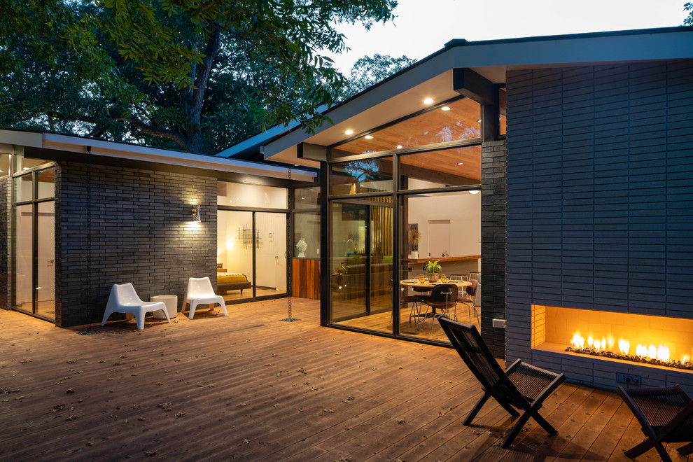Design ideas for a large midcentury backyard deck in Dallas with with fireplace and no cover.