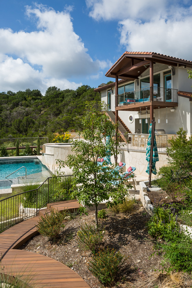 Photo of a large mediterranean backyard rectangular aboveground pool in Austin with a hot tub and tile.