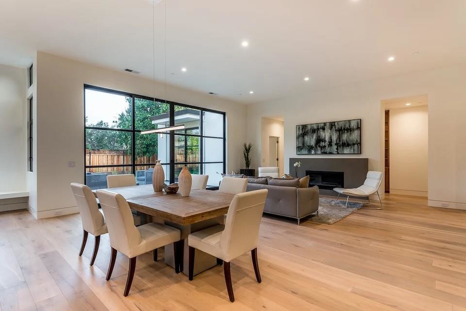 Large contemporary open plan dining in San Francisco with white walls, light hardwood floors, a ribbon fireplace, a plaster fireplace surround and beige floor.
