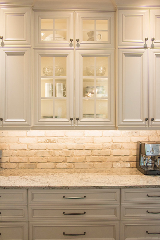 Eat-in kitchen - large transitional l-shaped eat-in kitchen idea with a double-bowl sink, shaker cabinets, white cabinets, beige backsplash, stainless steel appliances and an island