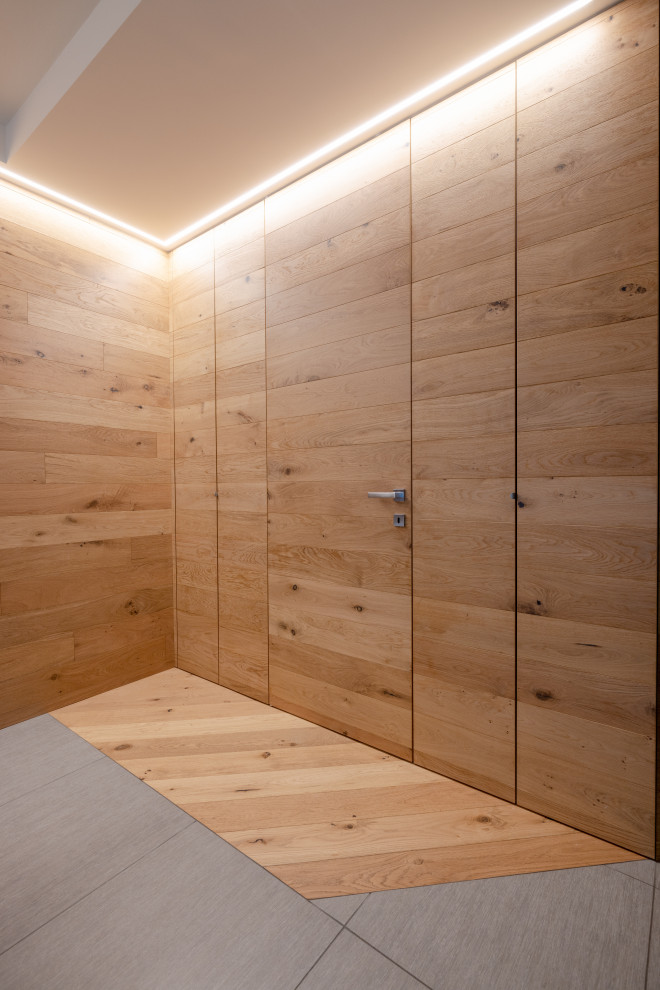 Cette image montre un très grand couloir design en bois avec un mur marron, un sol en bois brun, un sol beige et un plafond décaissé.