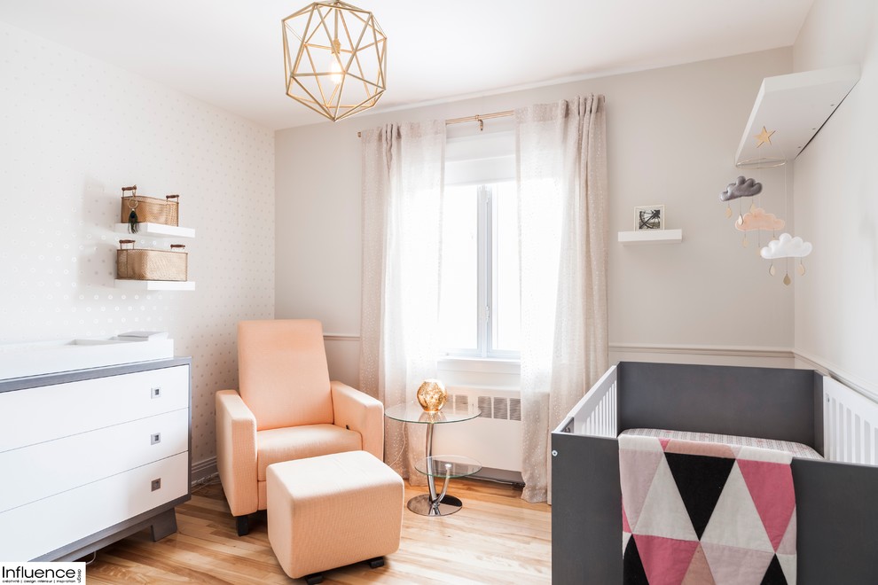 Design ideas for a small contemporary nursery for girls in Montreal with white walls and light hardwood floors.