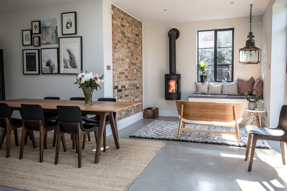 Design ideas for a mid-sized contemporary separate dining room in Buckinghamshire with white walls, concrete floors, a wood stove, a metal fireplace surround and grey floor.