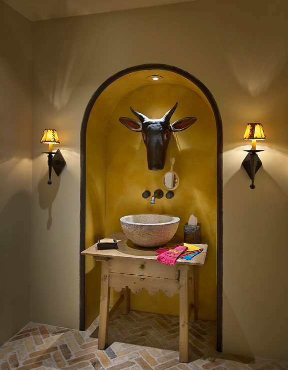Photo of a small mediterranean powder room in Phoenix with wood benchtops, a vessel sink, beige walls, brick floors, light wood cabinets and beige benchtops.