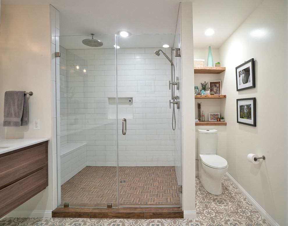 Large master bathroom in DC Metro with flat-panel cabinets, medium wood cabinets, an alcove shower, a two-piece toilet, white tile, ceramic tile, purple walls, cement tiles, an undermount sink, solid surface benchtops, brown floor, a hinged shower door, white benchtops, a shower seat, a double vanity and a floating vanity.