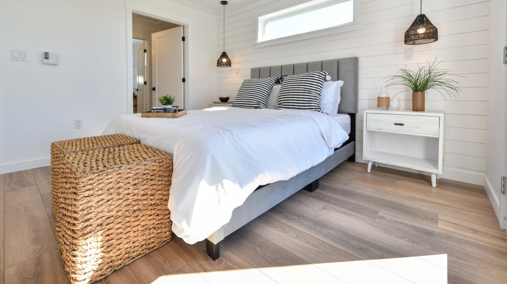 Aménagement d'une chambre d'amis bord de mer de taille moyenne avec un mur blanc, sol en stratifié, un sol marron et du lambris de bois.