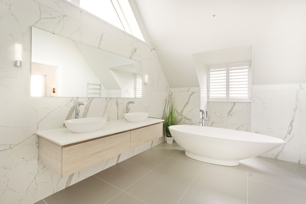 This is an example of a transitional master bathroom in Gloucestershire with flat-panel cabinets, light wood cabinets, a freestanding tub, white tile, ceramic tile, yellow walls, ceramic floors, quartzite benchtops, grey floor and white benchtops.
