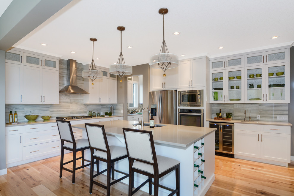 Inspiration for a transitional light wood floor and beige floor kitchen remodel in Calgary with gray backsplash, porcelain backsplash, an undermount sink, shaker cabinets, white cabinets, stainless steel appliances and an island