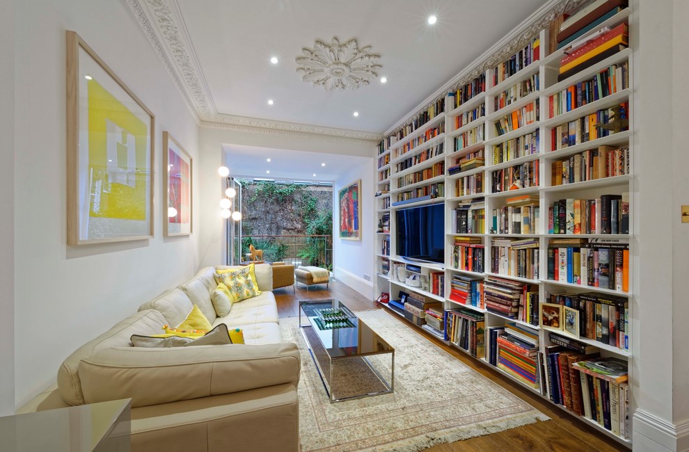 This is an example of a mid-sized transitional living room in London with a library, white walls, medium hardwood floors, a wall-mounted tv and brown floor.