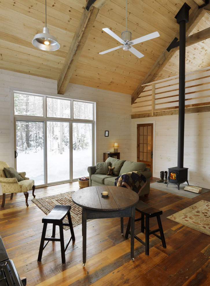 Country open concept living room in Burlington with beige walls, medium hardwood floors and a wood stove.