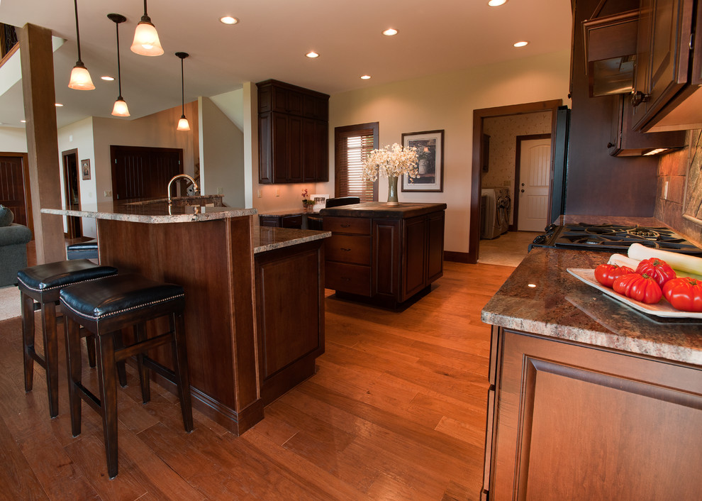 Open concept kitchen - large craftsman u-shaped medium tone wood floor and brown floor open concept kitchen idea with shaker cabinets, medium tone wood cabinets, granite countertops, multicolored backsplash, slate backsplash, stainless steel appliances, an island and a farmhouse sink