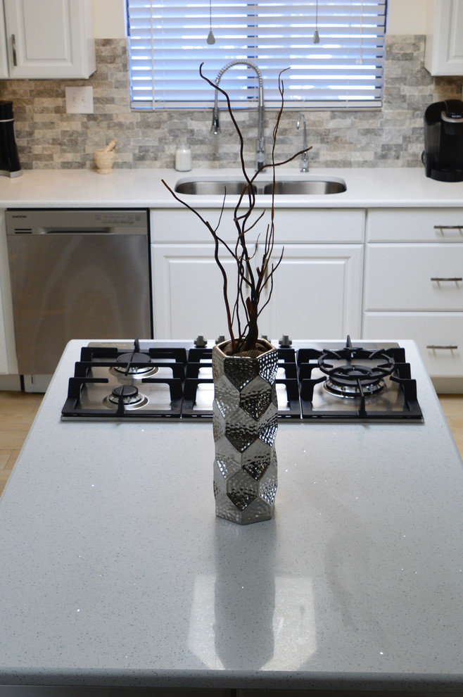 Example of a mid-sized transitional l-shaped porcelain tile enclosed kitchen design in Albuquerque with an undermount sink, raised-panel cabinets, white cabinets, quartz countertops, beige backsplash, porcelain backsplash, stainless steel appliances and no island