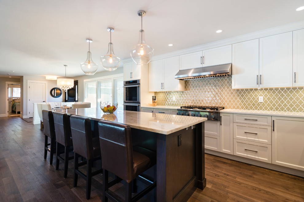 Inspiration for a mid-sized transitional l-shaped medium tone wood floor open concept kitchen remodel in Vancouver with an undermount sink, shaker cabinets, white cabinets, quartz countertops, green backsplash, glass tile backsplash, stainless steel appliances and an island