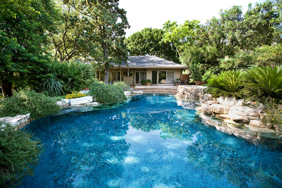 This is an example of a country backyard custom-shaped pool in Austin with brick pavers.