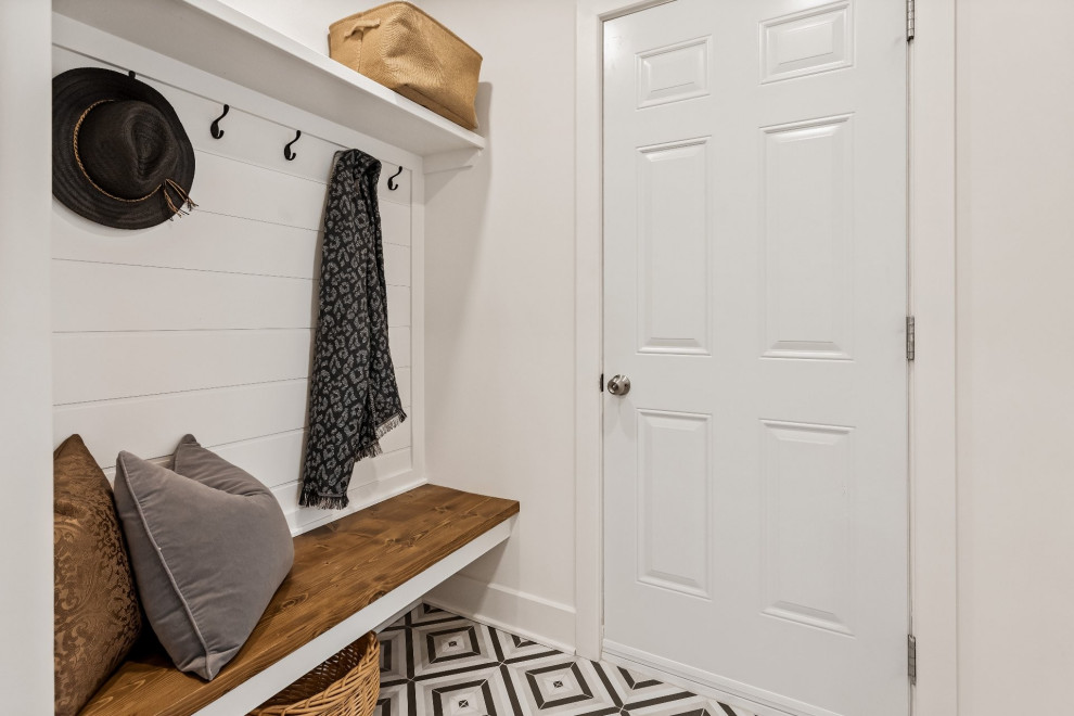 This is an example of a small country mudroom in Montreal with white walls, ceramic floors, a single front door, a red front door, multi-coloured floor and planked wall panelling.