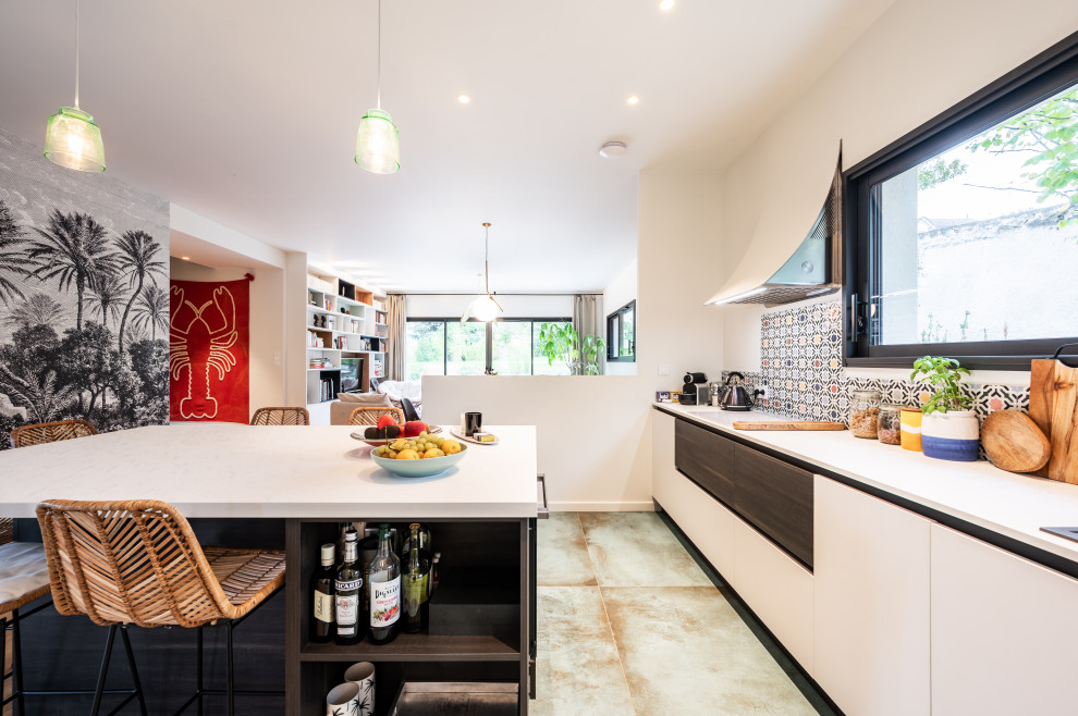 Mid-sized modern eat-in kitchen in Lyon with a single-bowl sink, white cabinets, laminate benchtops, multi-coloured splashback, ceramic splashback, black appliances, ceramic floors, with island, green floor and white benchtop.
