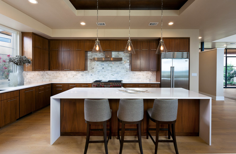 Inspiration for an arts and crafts u-shaped eat-in kitchen in Raleigh with a drop-in sink, flat-panel cabinets, medium wood cabinets, quartz benchtops, white splashback, glass tile splashback, stainless steel appliances, light hardwood floors and with island.