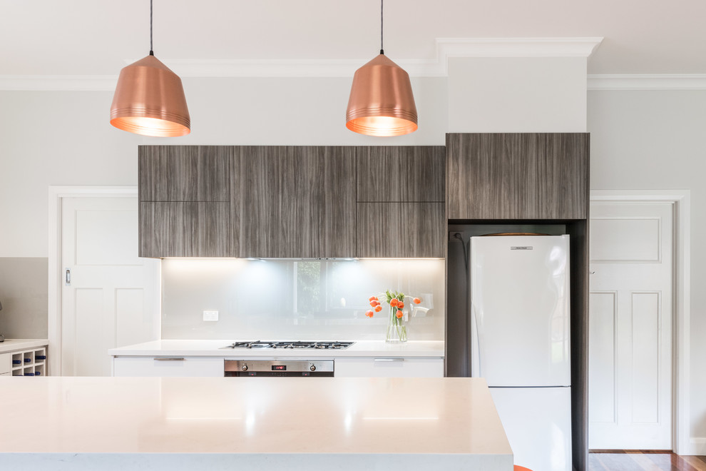 Inspiration for a mid-sized contemporary l-shaped eat-in kitchen in Melbourne with a drop-in sink, flat-panel cabinets, dark wood cabinets, quartz benchtops, grey splashback, glass sheet splashback, stainless steel appliances, medium hardwood floors and with island.