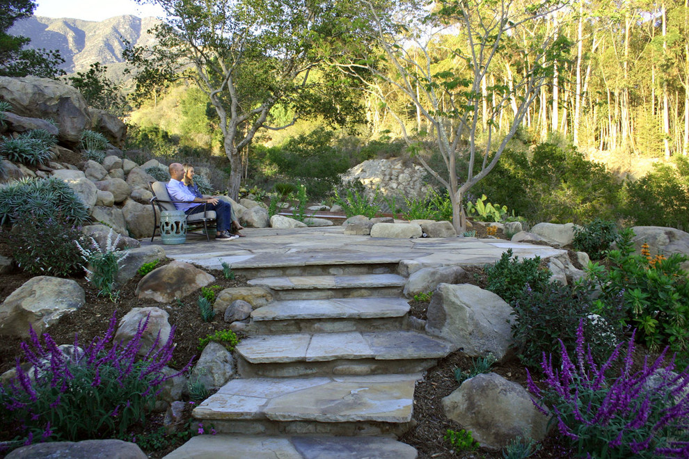 Design ideas for a mid-sized mediterranean sloped partial sun xeriscape in Santa Barbara with a garden path and natural stone pavers.