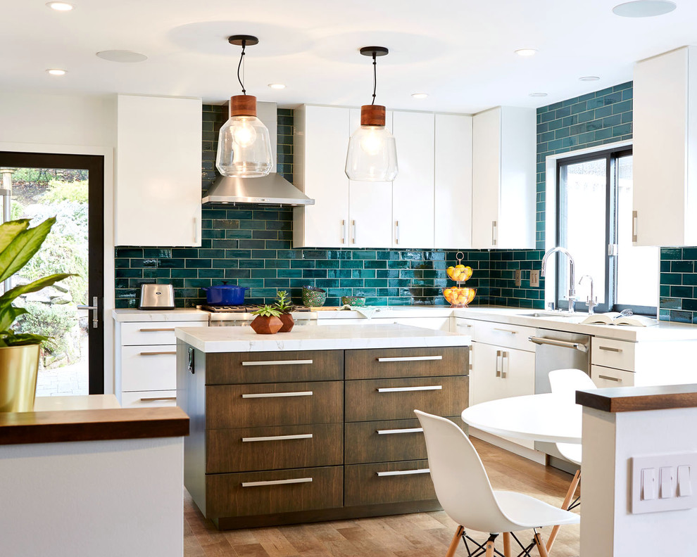 Contemporary eat-in kitchen in Minneapolis with ceramic splashback, white benchtop, an undermount sink, flat-panel cabinets, white cabinets, blue splashback, stainless steel appliances, medium hardwood floors, with island and beige floor.