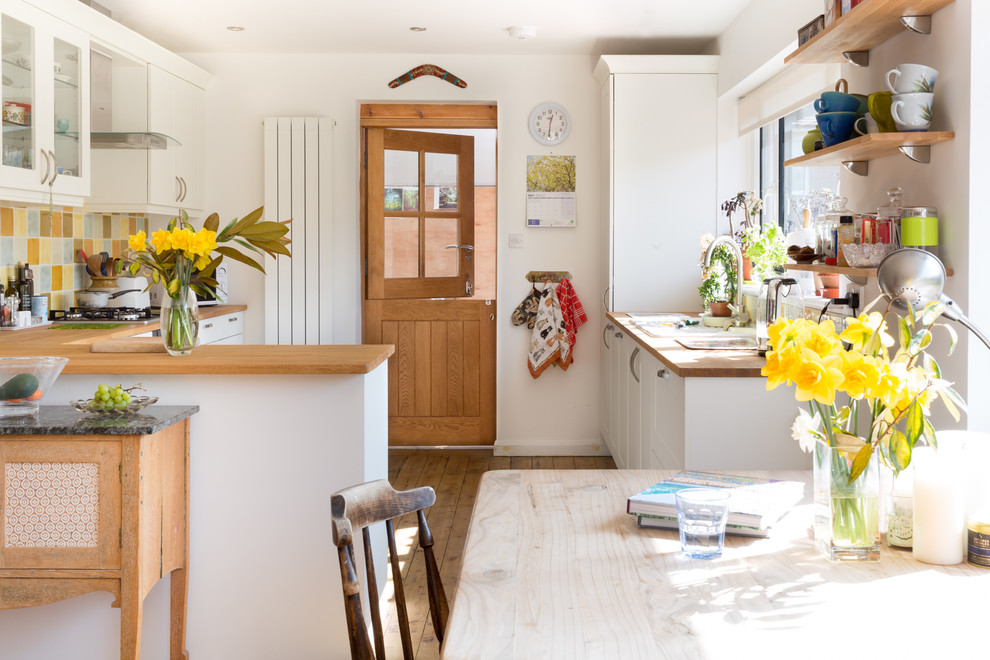Country u-shaped eat-in kitchen in Surrey with a drop-in sink, shaker cabinets, white cabinets, wood benchtops, multi-coloured splashback, medium hardwood floors, a peninsula, brown floor and brown benchtop.