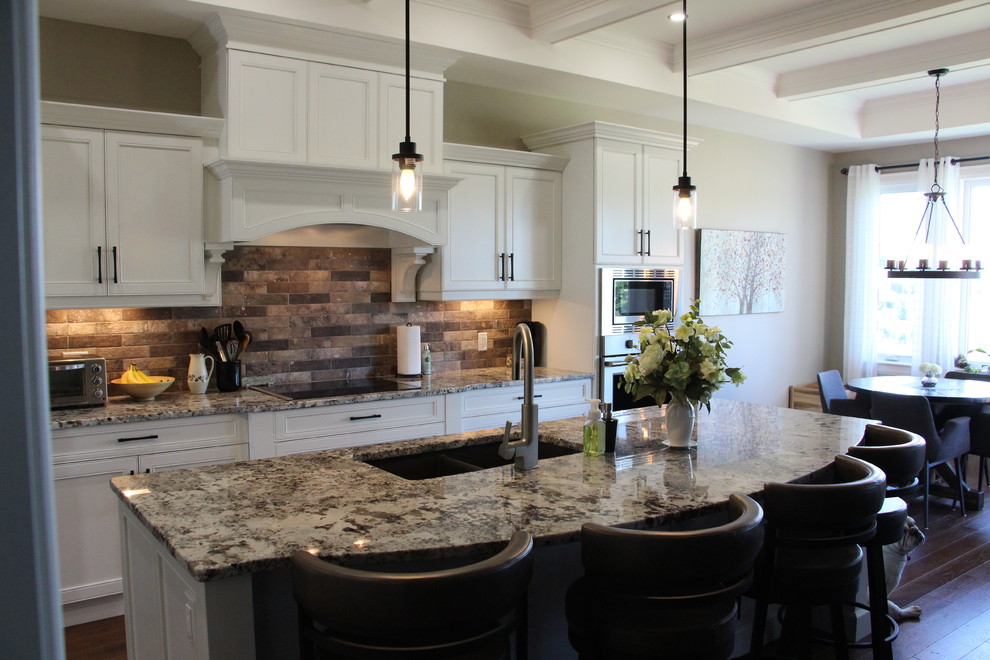 Large transitional l-shaped dark wood floor and brown floor eat-in kitchen photo in Toronto with an undermount sink, shaker cabinets, white cabinets, granite countertops, multicolored backsplash, subway tile backsplash, stainless steel appliances and an island