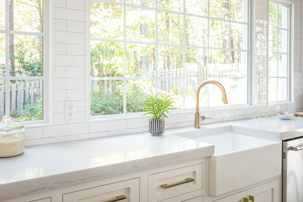 Inspiration for a small country single-wall open plan kitchen in Raleigh with a farmhouse sink, flat-panel cabinets, white cabinets, wood benchtops, white splashback, subway tile splashback, panelled appliances, light hardwood floors, with island and white benchtop.