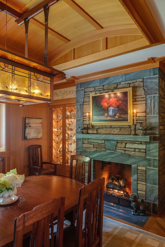 This is an example of a mid-sized arts and crafts separate dining room in Portland Maine with light hardwood floors, beige walls, a standard fireplace and a stone fireplace surround.