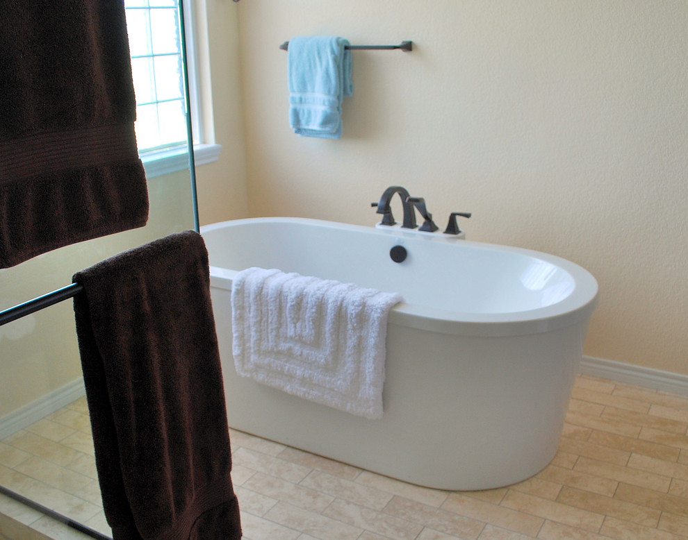 Example of a large mountain style master beige tile and subway tile travertine floor and beige floor freestanding bathtub design in Denver with shaker cabinets, dark wood cabinets, beige walls, an undermount sink, marble countertops and a hinged shower door