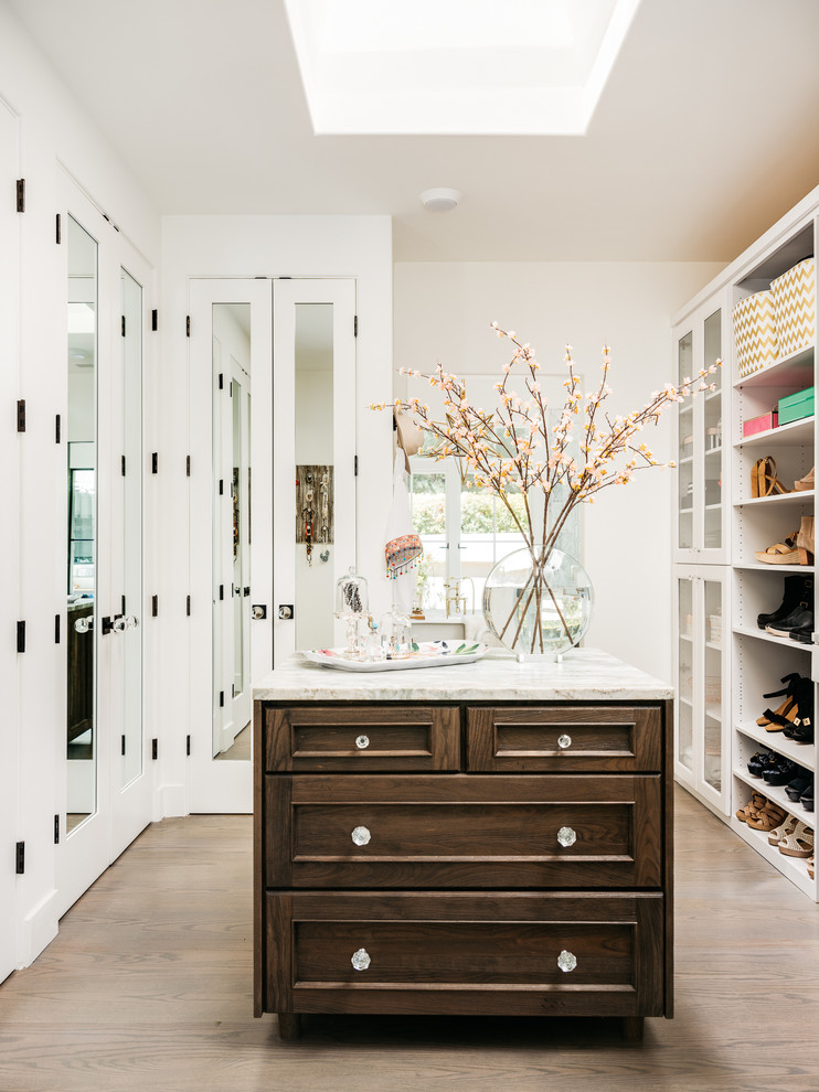 Photo of a large country gender-neutral walk-in wardrobe in San Francisco with recessed-panel cabinets, white cabinets, light hardwood floors and brown floor.