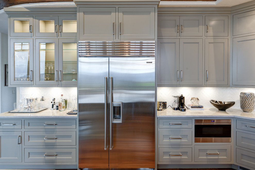 This is an example of an expansive transitional u-shaped eat-in kitchen in Salt Lake City with recessed-panel cabinets, grey cabinets, quartz benchtops, white splashback, ceramic splashback, stainless steel appliances and white benchtop.