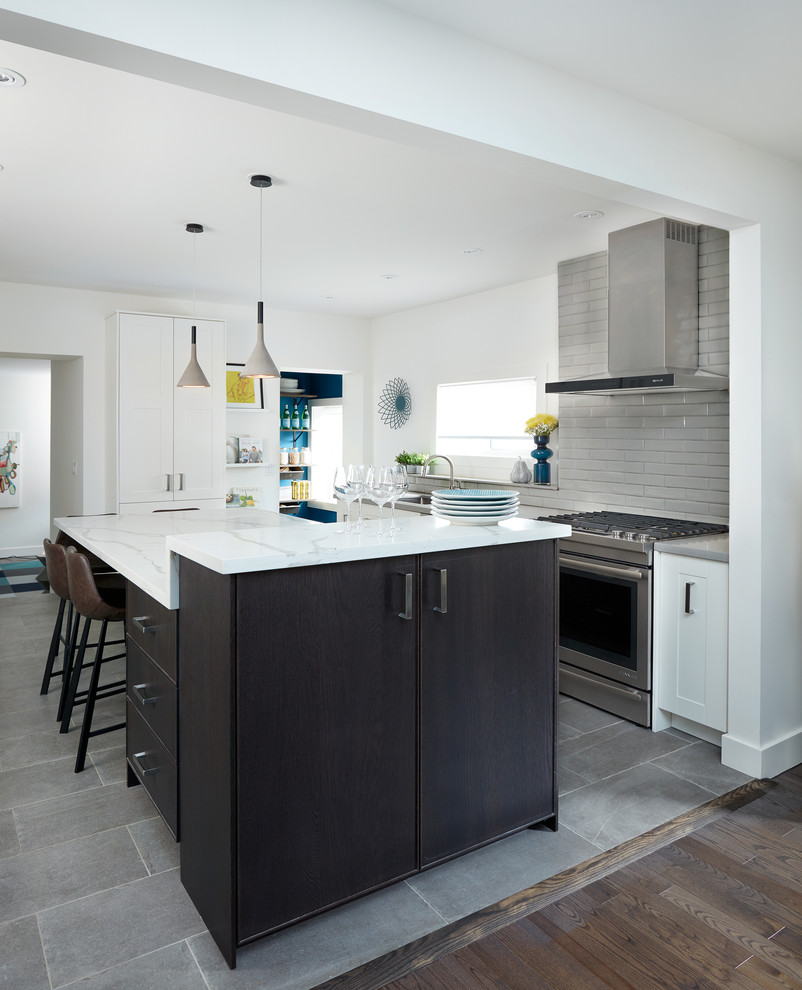 Contemporary kitchen in Toronto with a drop-in sink, shaker cabinets, dark wood cabinets, quartz benchtops, grey splashback, porcelain splashback, stainless steel appliances, slate floors, with island and grey floor.