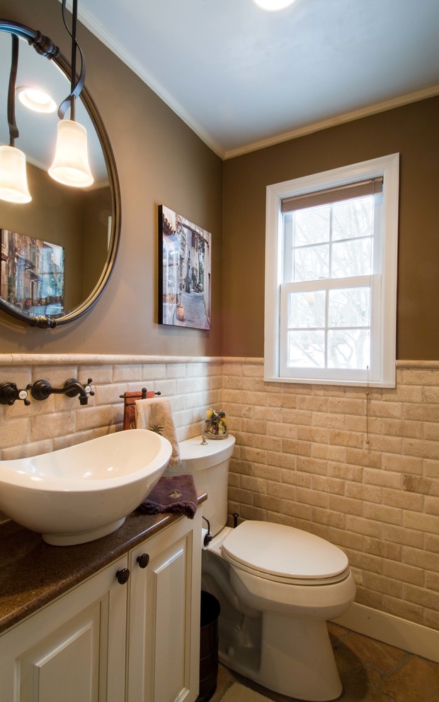 Inspiration for a small traditional bathroom in Minneapolis with raised-panel cabinets, white cabinets, a two-piece toilet, beige tile, stone tile, brown walls, limestone floors, a vessel sink and granite benchtops.