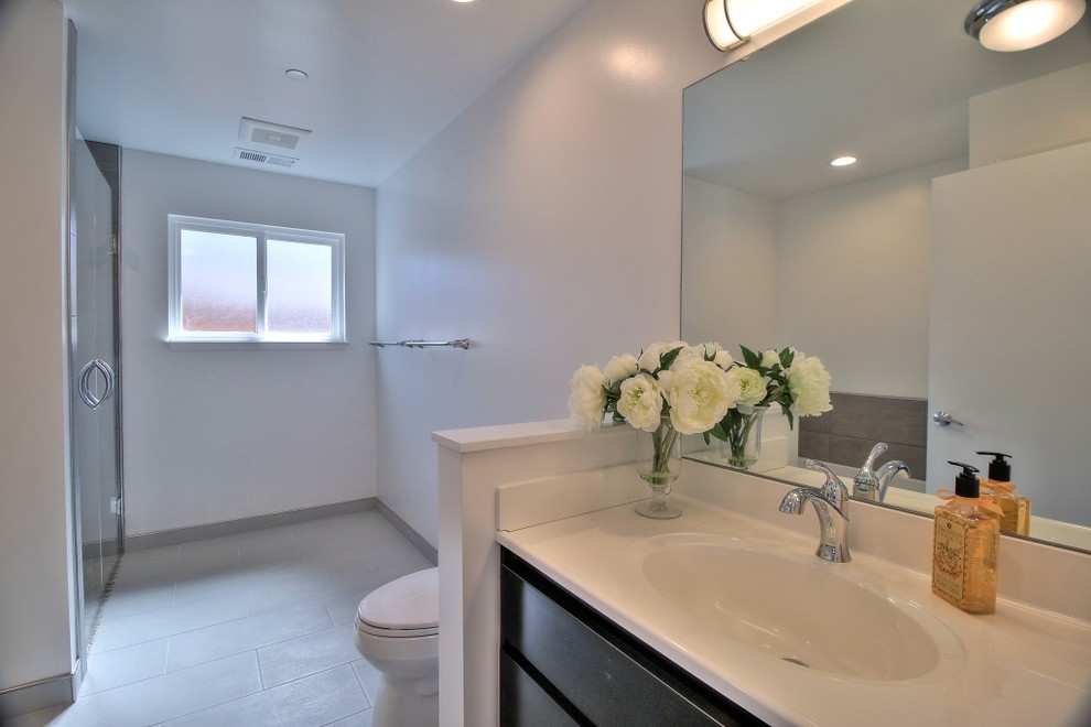 Photo of a mid-sized contemporary 3/4 bathroom in San Francisco with flat-panel cabinets, dark wood cabinets, a curbless shower, gray tile, porcelain tile, grey walls, porcelain floors, an integrated sink and quartzite benchtops.