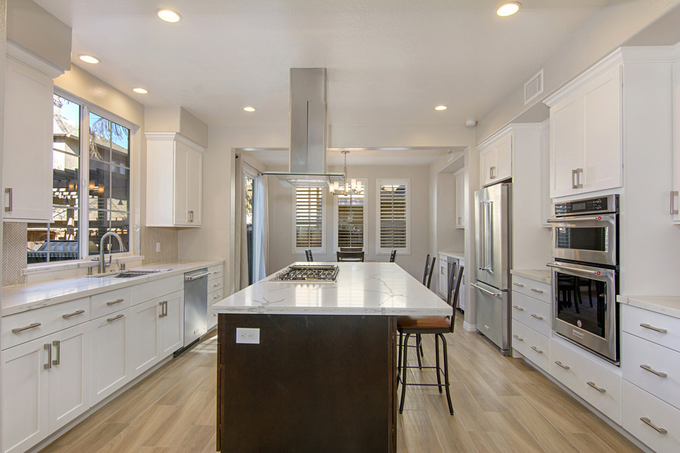 This is an example of a large modern u-shaped eat-in kitchen in San Diego with a drop-in sink, recessed-panel cabinets, white cabinets, quartzite benchtops, white splashback, ceramic splashback, stainless steel appliances, porcelain floors, with island and grey floor.