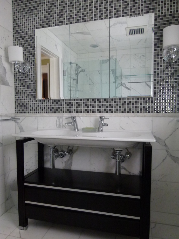 Photo of a mid-sized transitional master bathroom in New York with flat-panel cabinets, black cabinets, an open shower, black and white tile, mosaic tile, white walls, marble floors, an integrated sink, marble benchtops, a freestanding tub, a two-piece toilet, white floor and a hinged shower door.